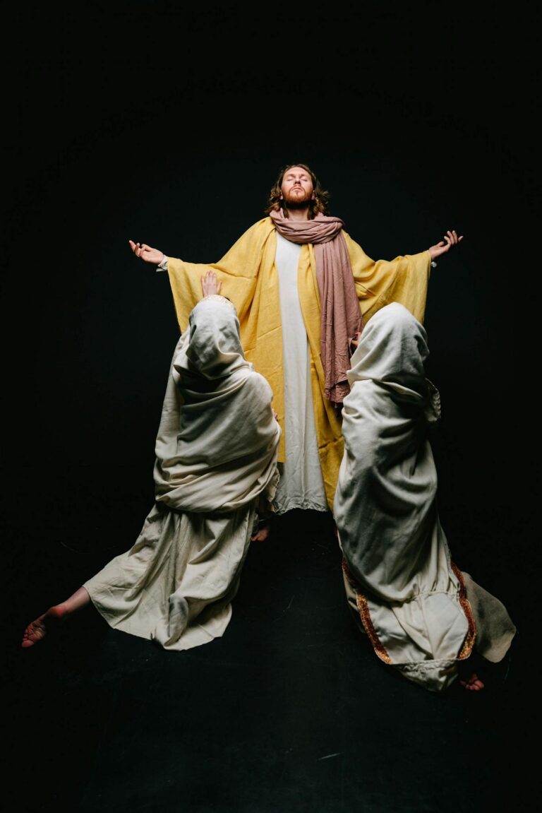 Artistic portrayal of Jesus Christ with followers in reverent pose on dark background.
