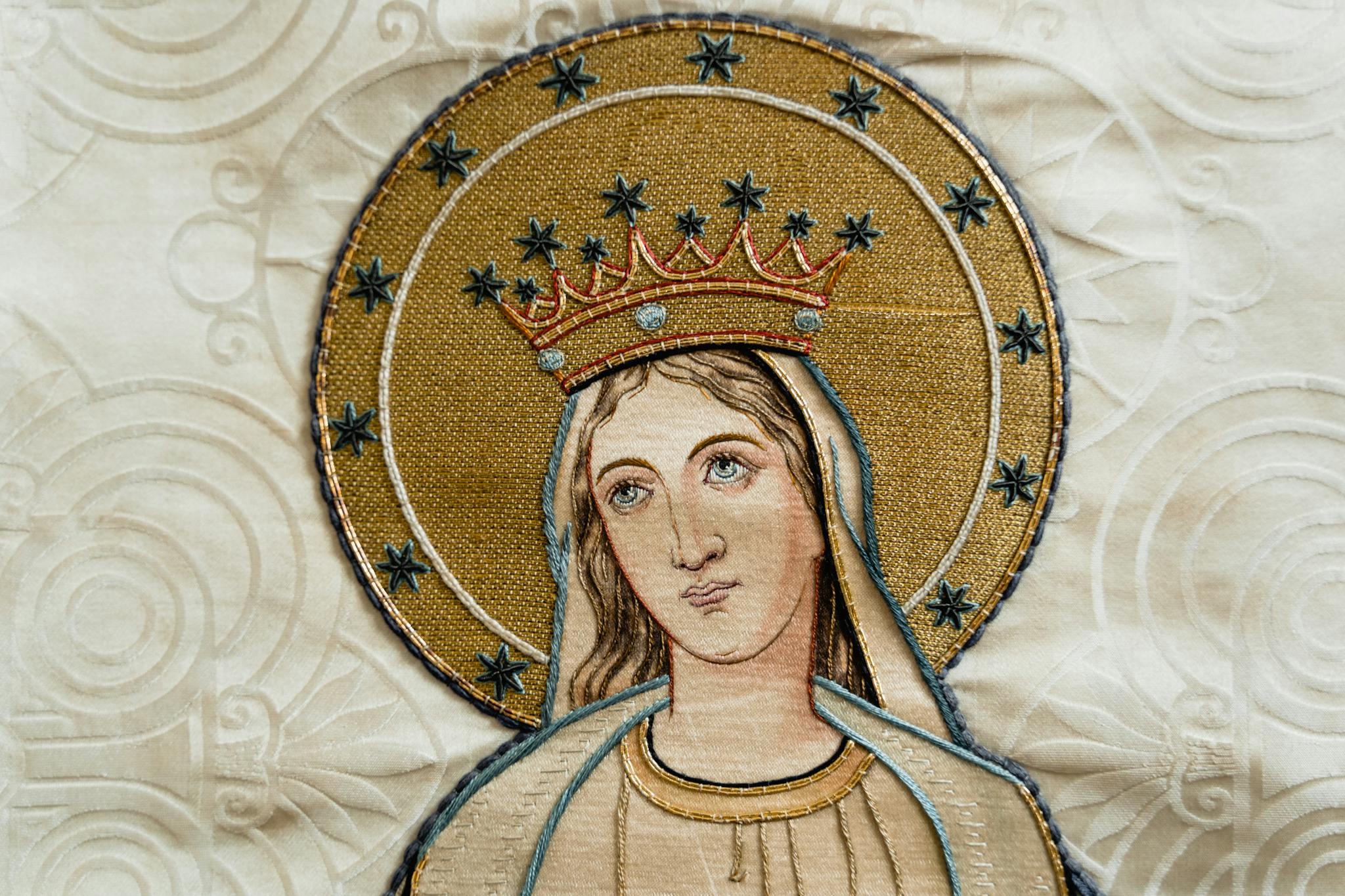 Beautifully detailed religious embroidery depicting a holy figure adorned in gold and stars.